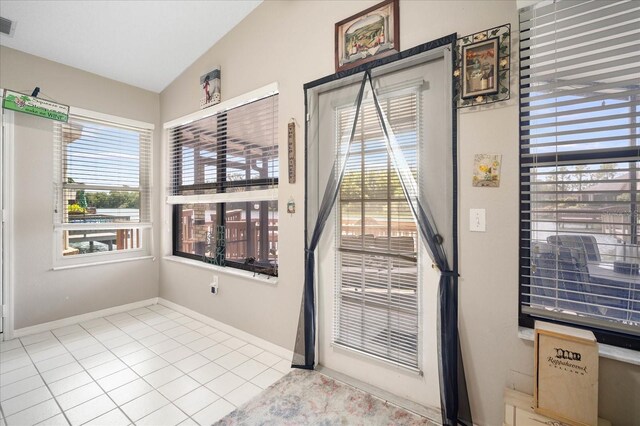 doorway with lofted ceiling and light tile patterned floors