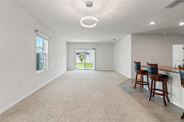 carpeted living room featuring a textured ceiling and a healthy amount of sunlight