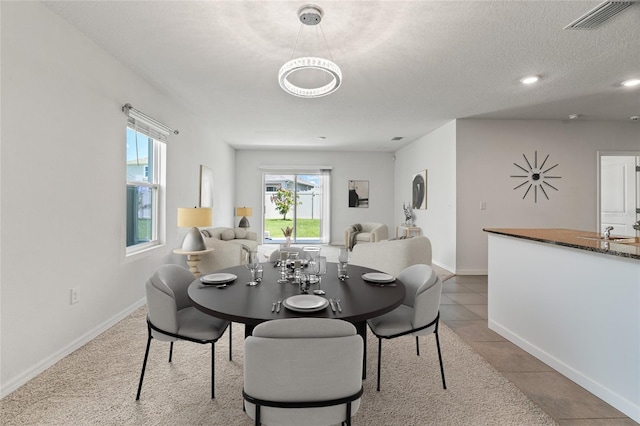 dining area with a textured ceiling and light tile patterned flooring