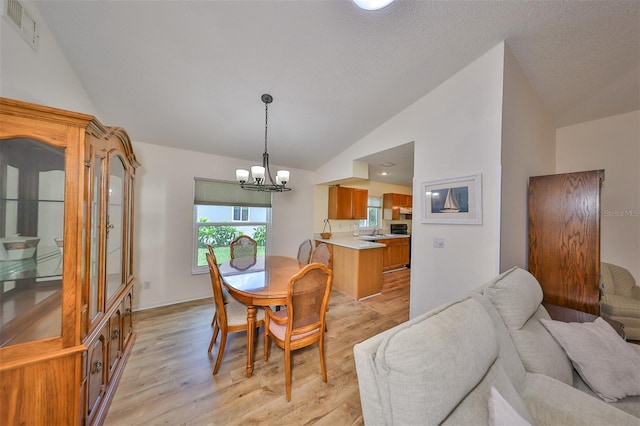 dining room featuring high vaulted ceiling, an inviting chandelier, light hardwood / wood-style flooring, and sink