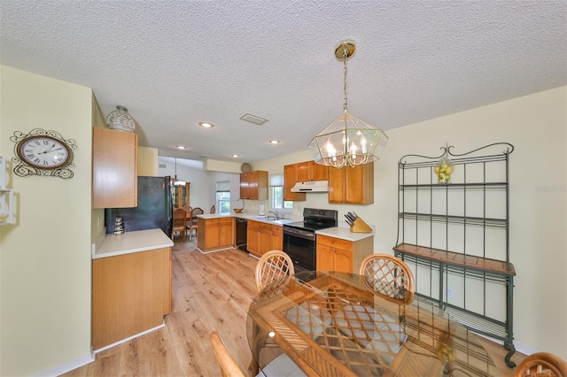 kitchen with sink, light hardwood / wood-style flooring, a textured ceiling, hanging light fixtures, and black appliances