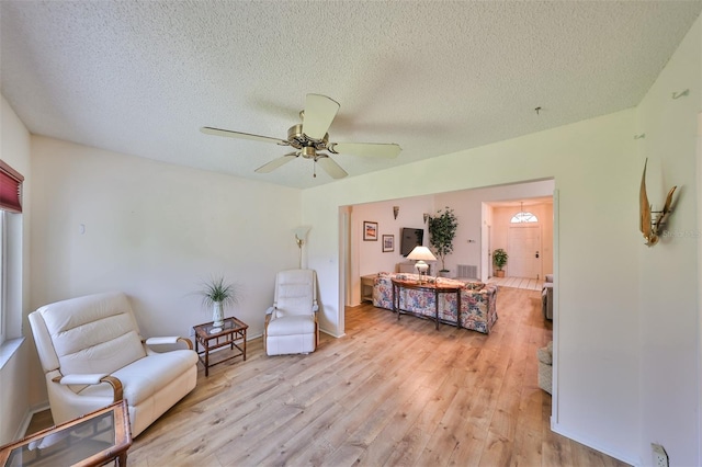 living area featuring a textured ceiling, light hardwood / wood-style flooring, and ceiling fan