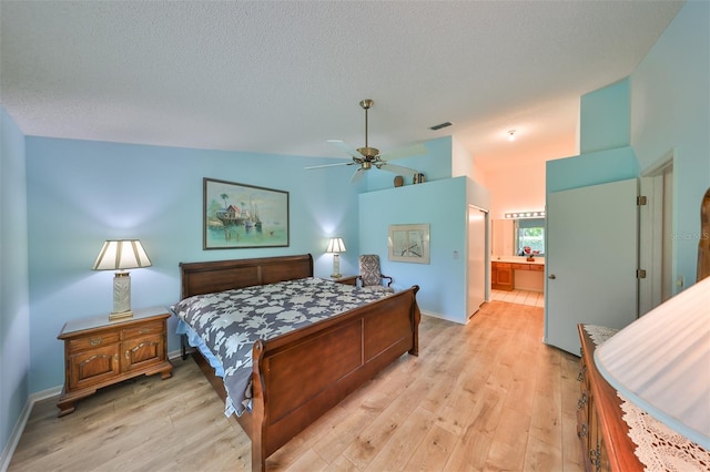 bedroom with ceiling fan, light hardwood / wood-style floors, connected bathroom, and a textured ceiling