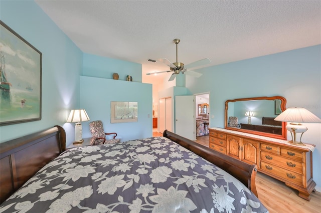 bedroom with light wood-type flooring, ceiling fan, ensuite bathroom, and a textured ceiling