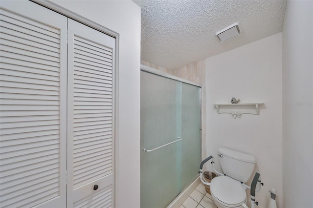 bathroom featuring toilet, walk in shower, tile patterned floors, and a textured ceiling