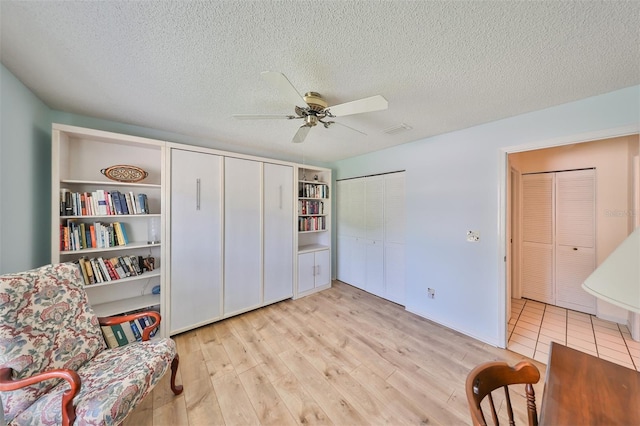 sitting room with ceiling fan, a textured ceiling, and light tile patterned floors