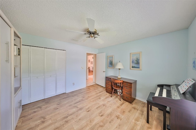 sitting room featuring ceiling fan, light hardwood / wood-style floors, and a textured ceiling