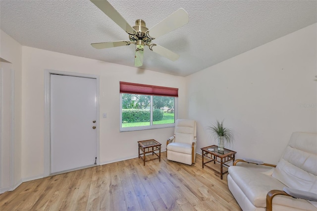 sitting room with ceiling fan, light hardwood / wood-style floors, and a textured ceiling