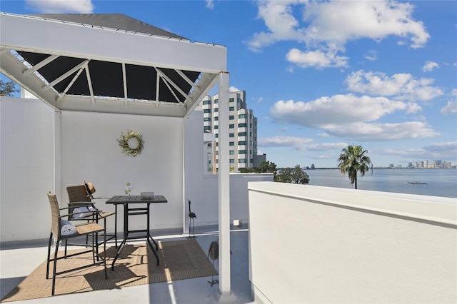 view of patio with a city view, a balcony, and a water view