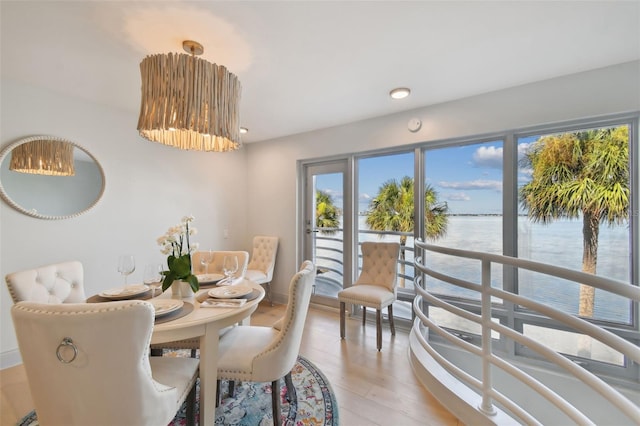 dining area with light wood finished floors and a water view