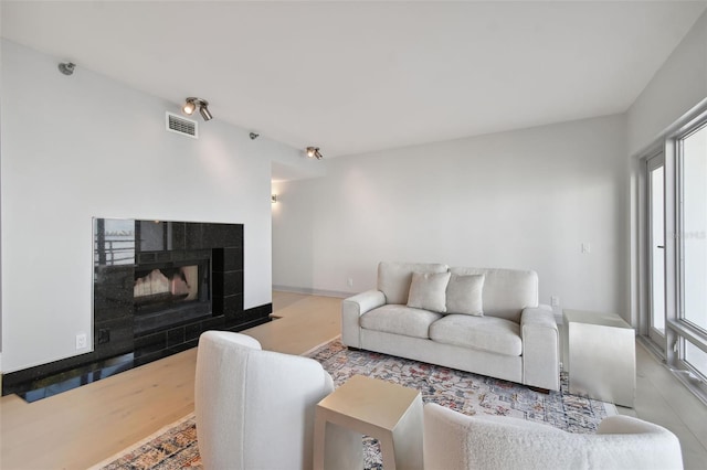 living room featuring a tile fireplace, plenty of natural light, and light wood-type flooring