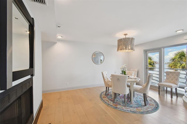 dining room featuring visible vents, baseboards, light wood finished floors, and a multi sided fireplace