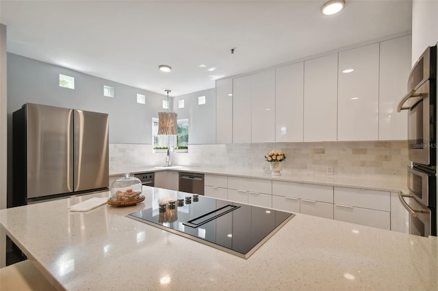 kitchen with appliances with stainless steel finishes, white cabinetry, pendant lighting, and light stone counters