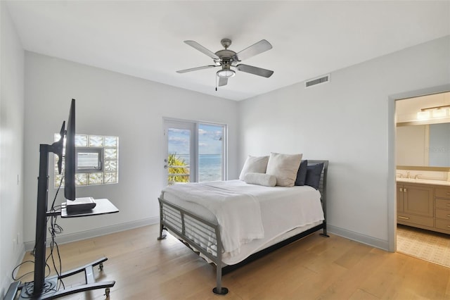 bedroom featuring sink, light wood-type flooring, ceiling fan, and connected bathroom