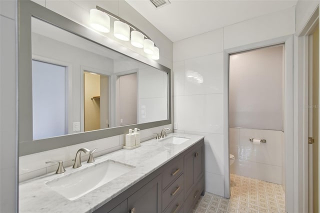 full bathroom featuring a sink, visible vents, toilet, and double vanity