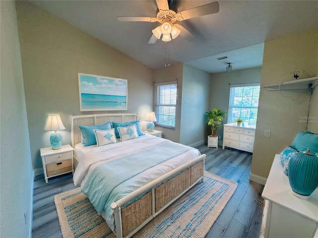 bedroom featuring dark hardwood / wood-style floors, ceiling fan, vaulted ceiling, and multiple windows