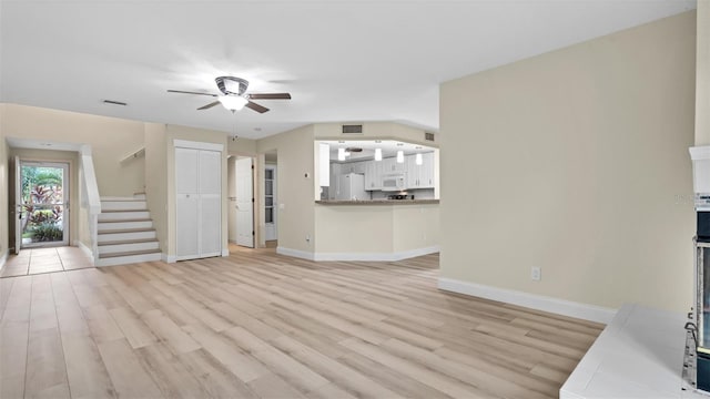 unfurnished living room with light wood-type flooring and ceiling fan