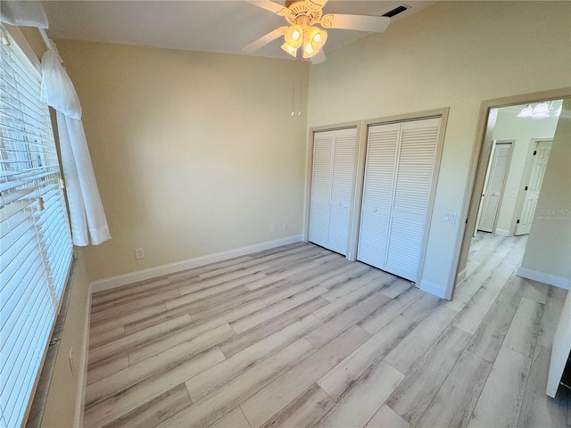 unfurnished bedroom featuring ceiling fan, light hardwood / wood-style floors, and two closets