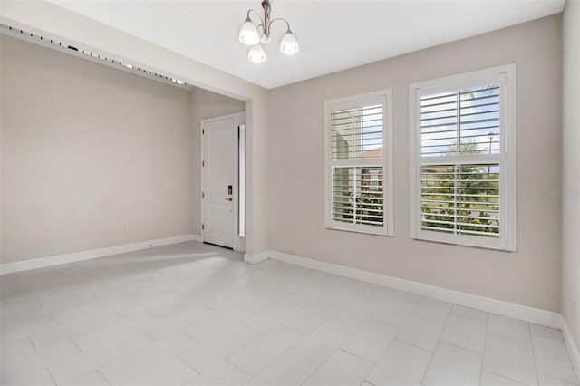 tiled spare room with an inviting chandelier