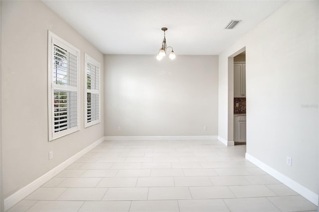 tiled empty room featuring a notable chandelier