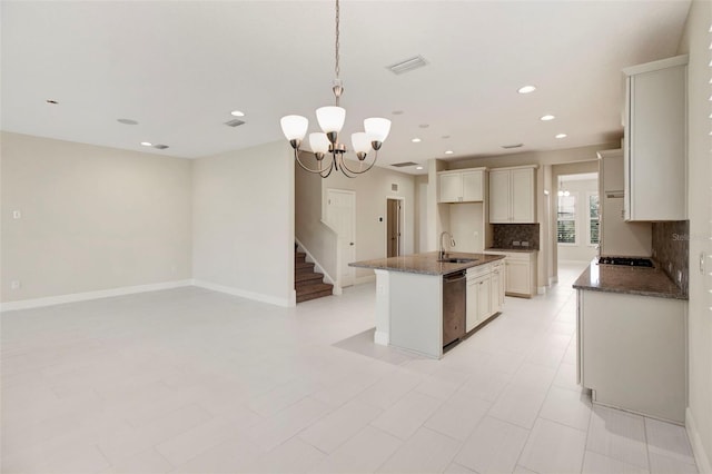 kitchen featuring sink, a kitchen island with sink, a chandelier, decorative backsplash, and appliances with stainless steel finishes