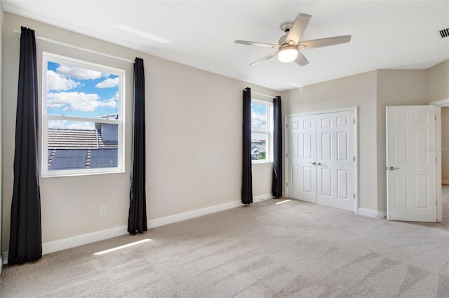 unfurnished bedroom with a closet, light colored carpet, and ceiling fan