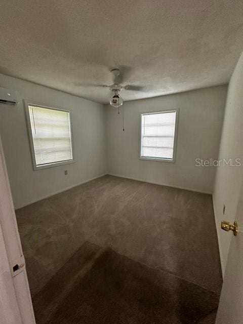 carpeted empty room featuring a textured ceiling, ceiling fan, and a wall mounted air conditioner