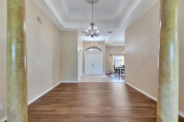 entryway featuring dark hardwood / wood-style floors, a raised ceiling, and a notable chandelier