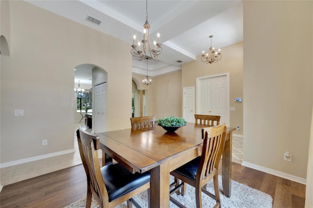 dining area featuring dark wood-type flooring, a notable chandelier, and a tray ceiling