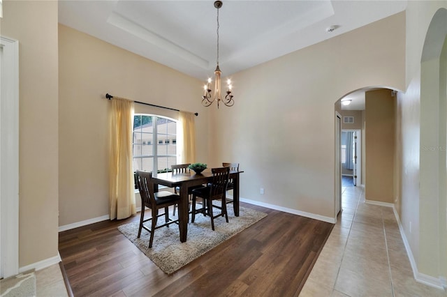 dining room with a tray ceiling, a chandelier, and hardwood / wood-style floors