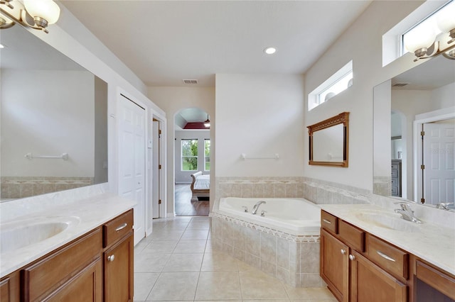 bathroom with vanity, a relaxing tiled tub, and tile patterned flooring