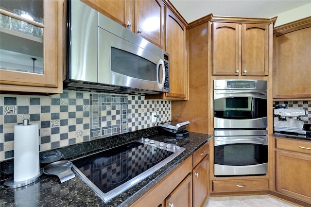 kitchen featuring dark stone countertops, light tile patterned floors, tasteful backsplash, and stainless steel appliances