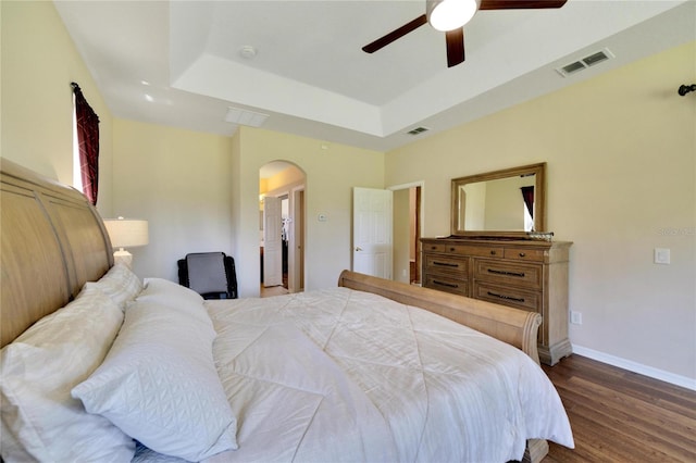 bedroom featuring dark wood-type flooring, ceiling fan, and a raised ceiling