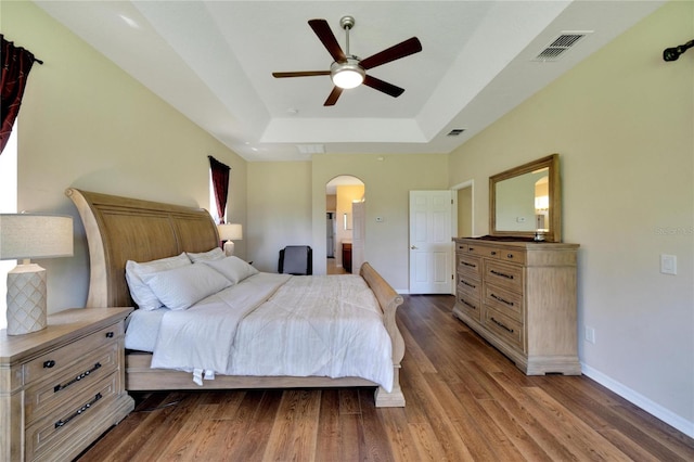 bedroom featuring a tray ceiling, dark hardwood / wood-style flooring, and ceiling fan