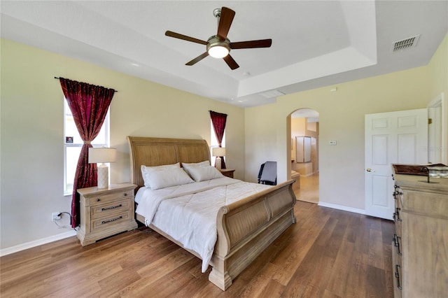 bedroom featuring a tray ceiling, ceiling fan, and dark hardwood / wood-style floors