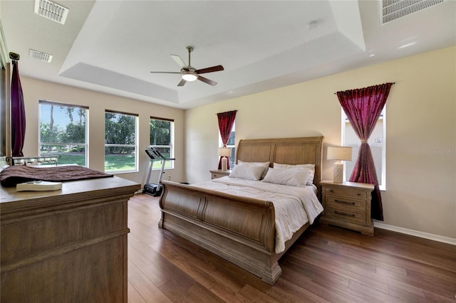 bedroom with a tray ceiling, dark hardwood / wood-style flooring, and ceiling fan