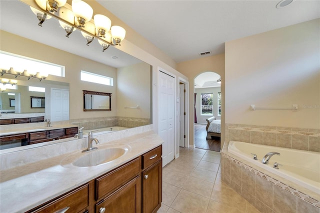 bathroom with vanity, tile patterned flooring, and tiled bath