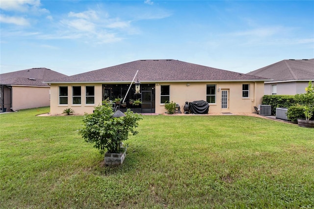 back of property with a yard and central air condition unit