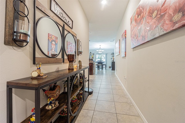 hall with light tile patterned flooring and an inviting chandelier