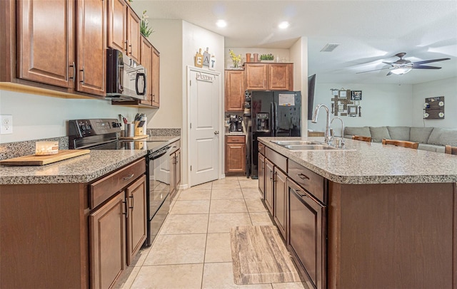 kitchen featuring ceiling fan, range with electric cooktop, an island with sink, light tile patterned floors, and sink