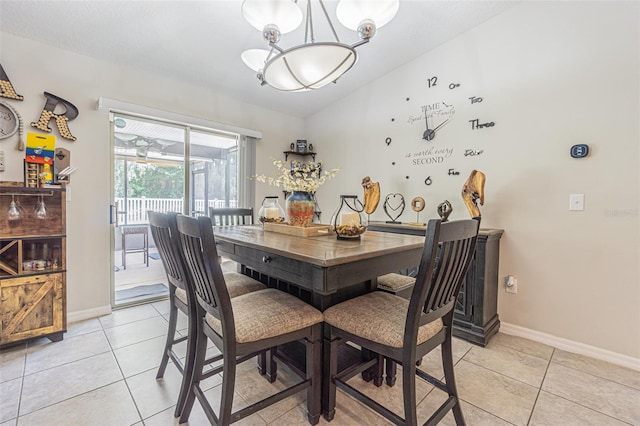 dining space with light tile patterned flooring, vaulted ceiling, and a chandelier