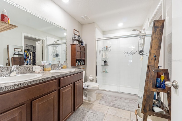 bathroom with a shower with door, toilet, vanity, and tile patterned floors