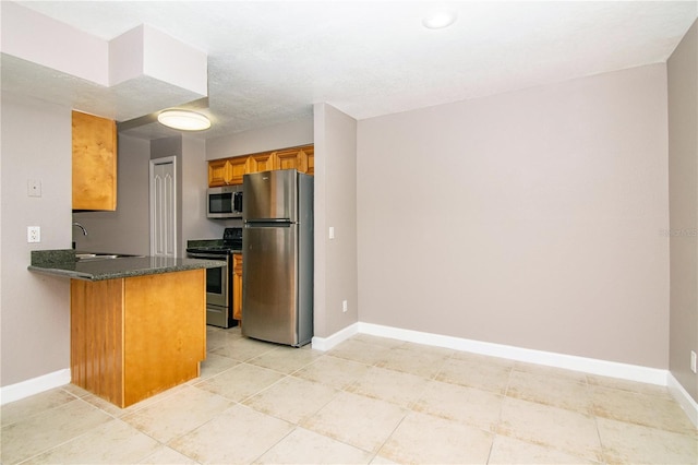 kitchen featuring dark stone counters, appliances with stainless steel finishes, sink, kitchen peninsula, and light tile patterned flooring