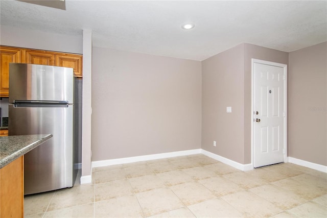 kitchen with light tile patterned floors and stainless steel refrigerator