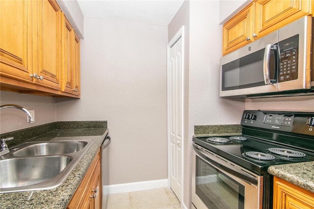 kitchen featuring light tile patterned floors, appliances with stainless steel finishes, sink, and dark stone counters