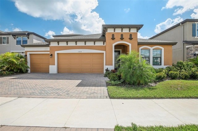 view of front of property featuring a garage, decorative driveway, and stucco siding