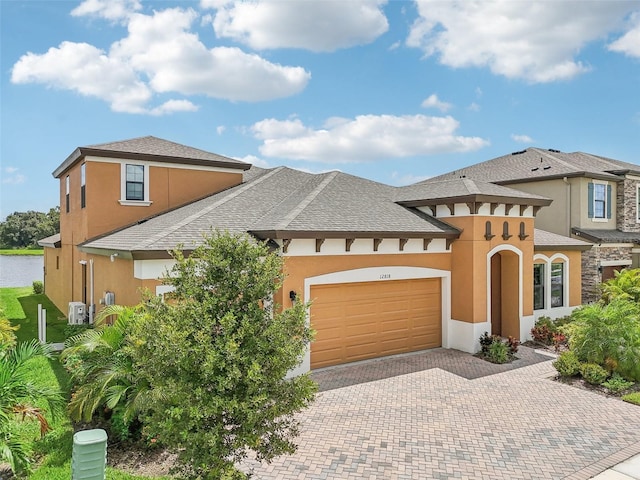 view of front of house featuring roof with shingles, decorative driveway, an attached garage, and stucco siding