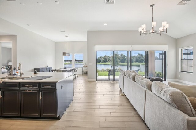 kitchen featuring pendant lighting, sink, a water view, and a kitchen island with sink