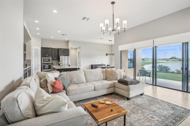 living area with visible vents, light wood-style flooring, a water view, an inviting chandelier, and recessed lighting