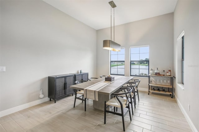 dining area featuring light wood-type flooring, high vaulted ceiling, and a water view